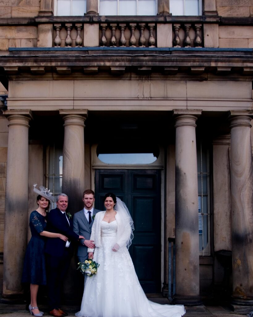 Boda: Novios con sus padres frente a edificio clásico. BodasPro & Emocionartestudio