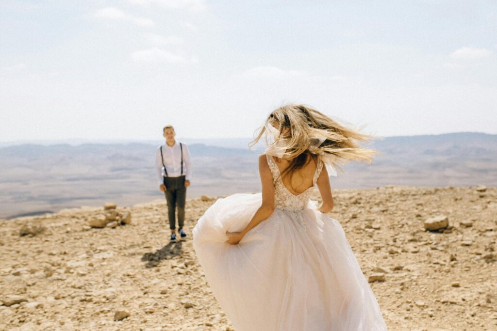 Esta imagen refleja las tendencias de bodas para 2025, incluyendo escenarios naturales y desérticos para ceremonias, así como atuendos simples pero elegantes que destacan en entornos al aire libre