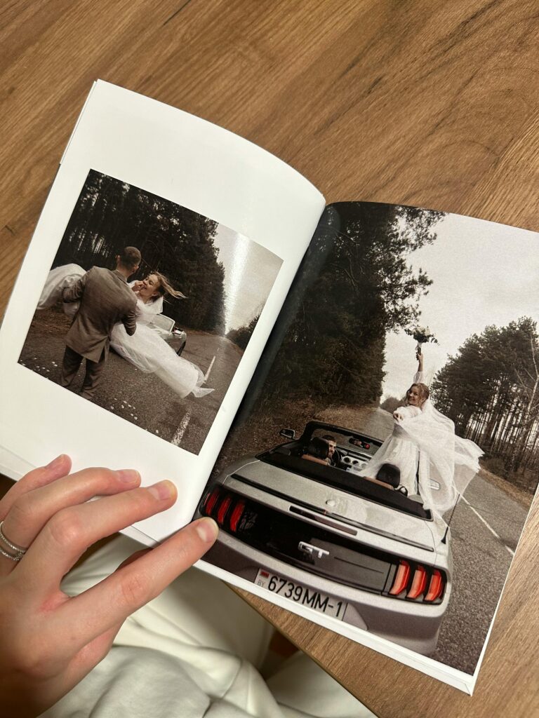 Primer plano de un álbum de boda abierto, con una mano sosteniéndolo y fotos de la boda visibles