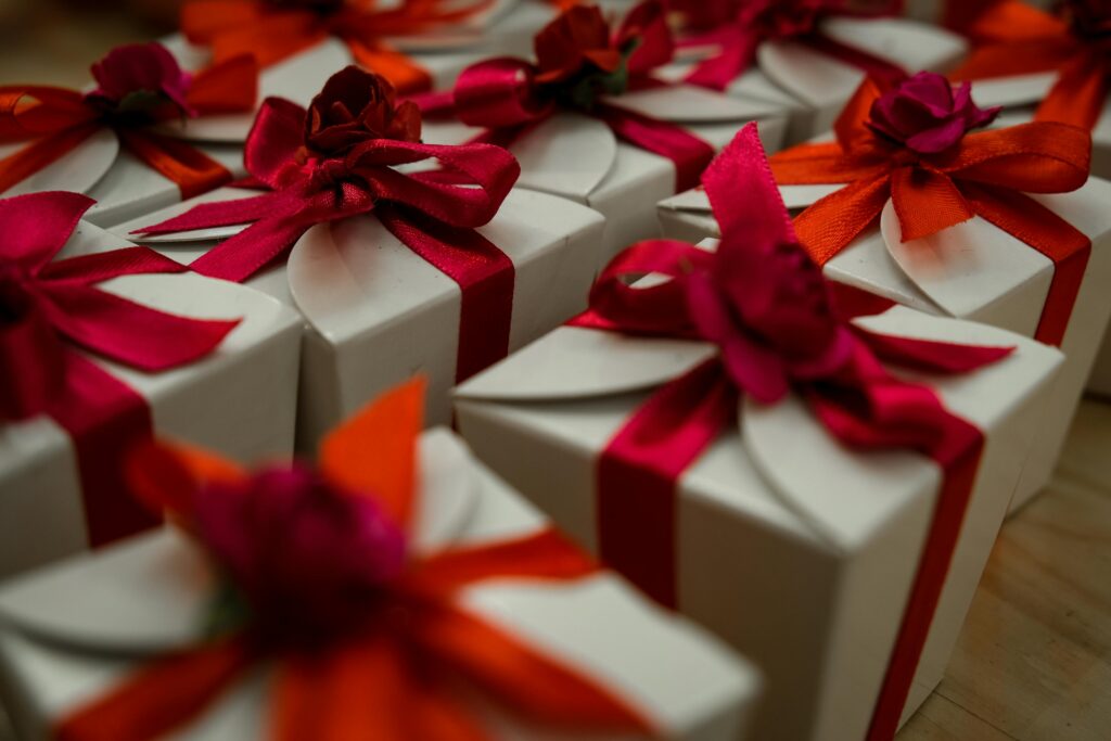 Ideas originales para regalos de boda: pequeños obsequios envueltos en cajas blancas con lazos de colores y detalles florales, listos para ser entregados a los invitados como recuerdo del enlace.