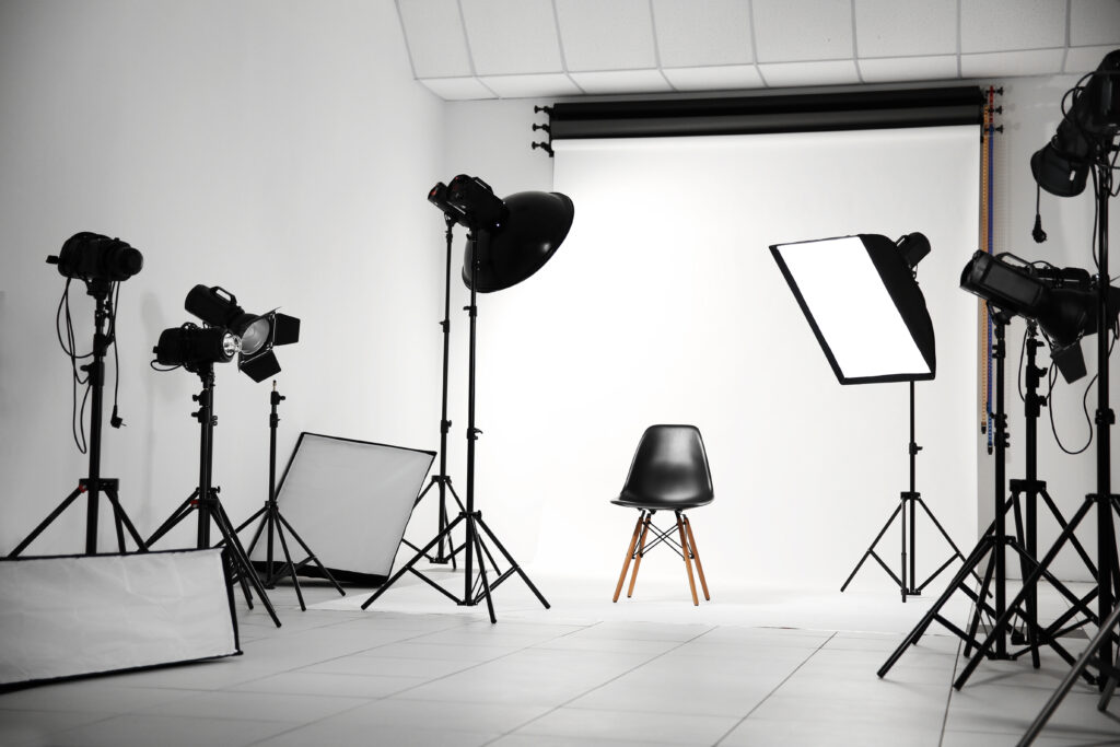 Un estudio fotográfico vacío con una silla solitaria en el centro, rodeada de equipo de iluminación y telones de fondo.